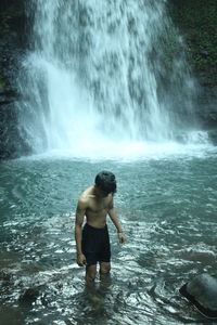 Full length of shirtless man standing in sea