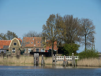 Houses and trees by lake against clear sky