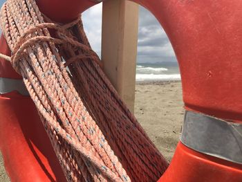 Close-up of rope tied on beach against sky