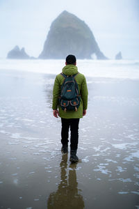 Rear view of man with backpack walking at beach