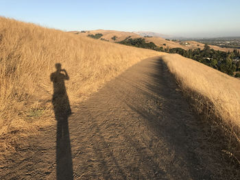 Shadow of person on field against sky