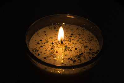 Close-up of lit candle in darkroom