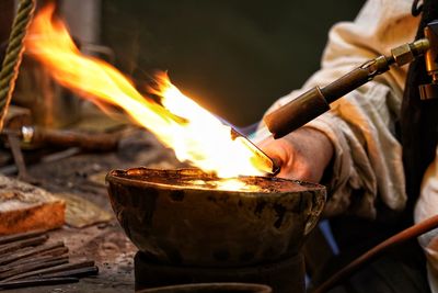 Close- up to hands doing medieval craft with fire for heating metall