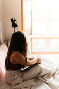 Woman sitting on bed at home