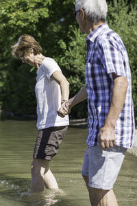 Active senior couple walking in lake against trees