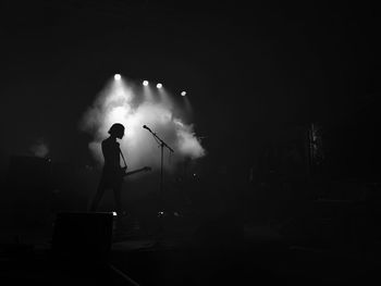Rear view of silhouette person playing guitar during concert