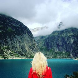 Female hiker standing in front of lake against sky