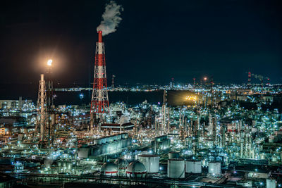 Illuminated factory against sky at night