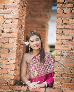 Portrait of beautiful young woman against brick wall