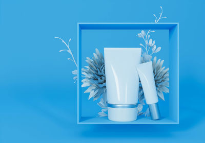 Flower vase on table against blue background
