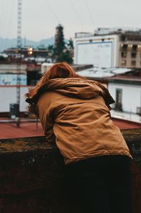 Rear view of woman standing on street against buildings in city