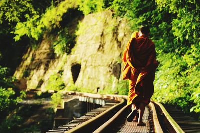 Rear view of monk walking on railroad track