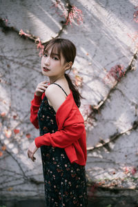 Side view of young woman standing against wall