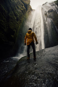 Full length of man standing against waterfall in cave