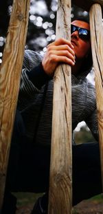 Midsection of men holding tree trunk