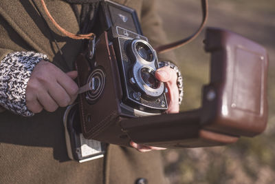 Midsection of woman with antique camera standing on grass field