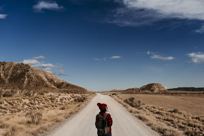 Spain, navarre, female tourist standing in middle of empty dirt road in bardenas reales