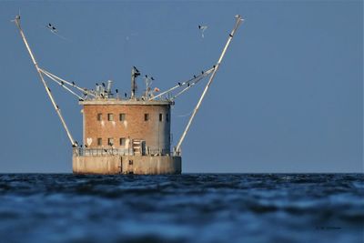 Built structure by sea against clear sky