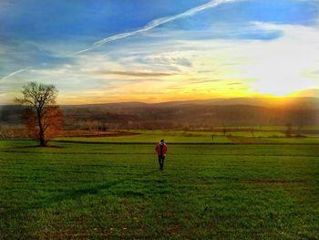 Man on field against sky during sunset