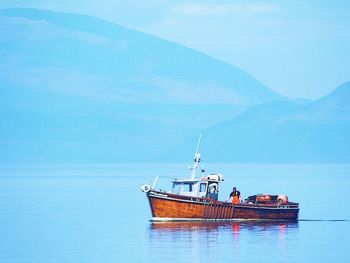 Fishing boat sailing in sea against sky