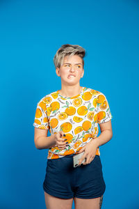 Portrait of smiling young woman against blue background