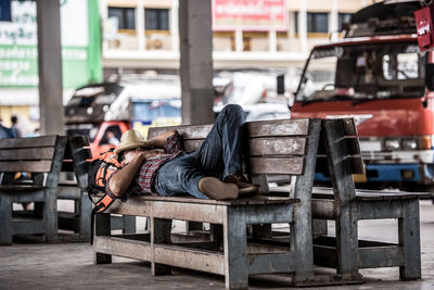 Male tourist sleeping on bench in city