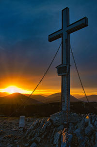 Cross on mountain against sky during sunset