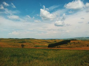 Scenic view of field against cloudy sky