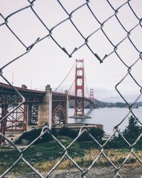 Suspension bridge seen through chainlink fence