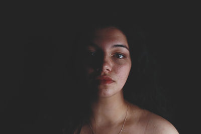 Close-up portrait of young woman over black background