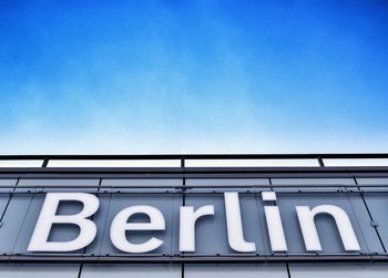 Low angle view of berlin text on wall against sky