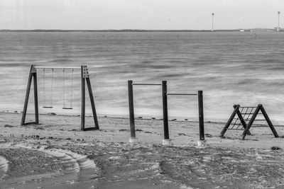 Wooden posts on beach against sky