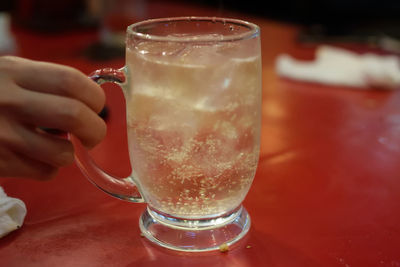 Close-up of hand holding drink on table