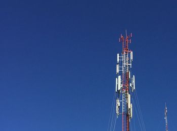 Low angle view of communications tower against clear blue sky