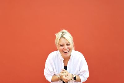 Portrait of woman laughing against orange background