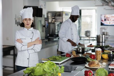 Chef standing with arms crossed at kitchen counter