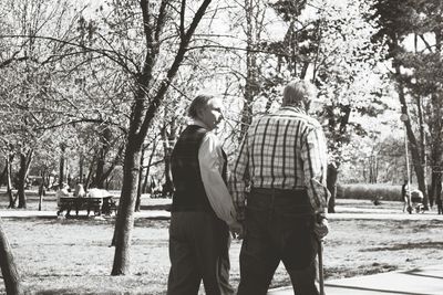 Rear view of couple standing by trees in city