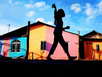 Full length of woman standing by building against sky