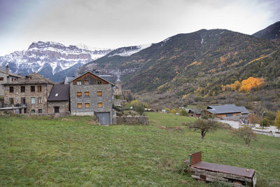 Houses on field by mountain against sky