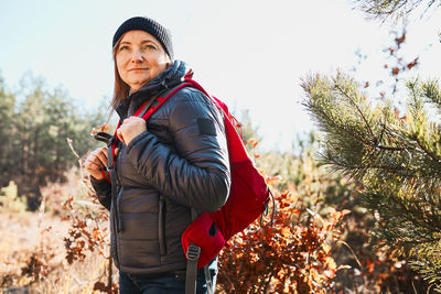 Happy woman enjoying hike on sunny vacation day. female with backpack walking through forest