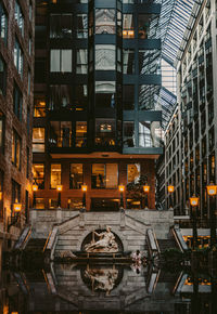 Reflection of statue in pond against building