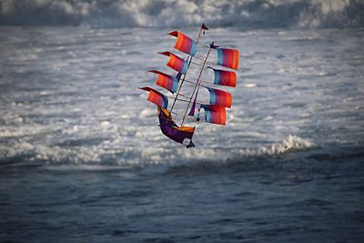 Colorful boat kite flying against sea