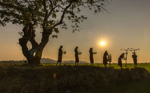 Silhouette people standing on field against sky during sunset