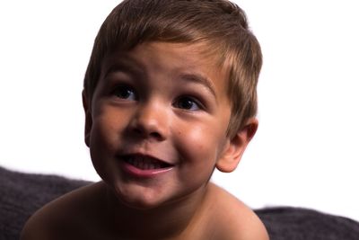 Close-up of shirtless boy looking away against white background