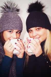 Portrait of young women wearing warm clothes while drinking coffee