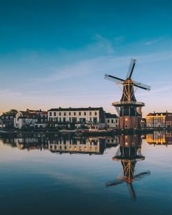 Traditional windmill by buildings against blue sky