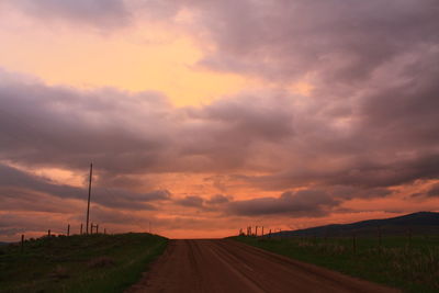 Road amidst land against sky during sunset
