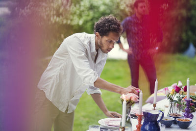 Young man lighting candles on table at garden party