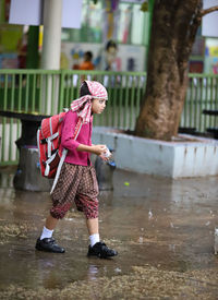 Full length of woman standing on wet umbrella during rainy season