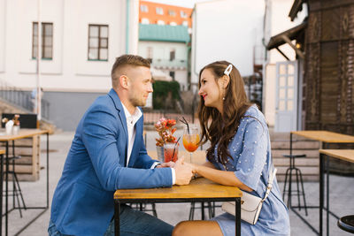 Beautiful couple in love is sitting at a table in an outdoor cafe on a date person
